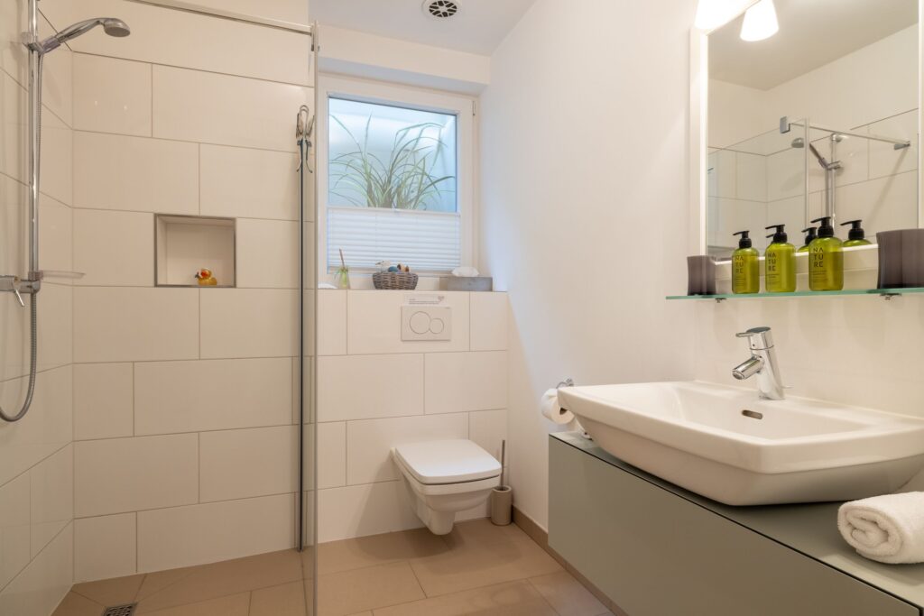 Badezimmer mit Waschbecken und Dusche in Ferienwohnung auf Sylt